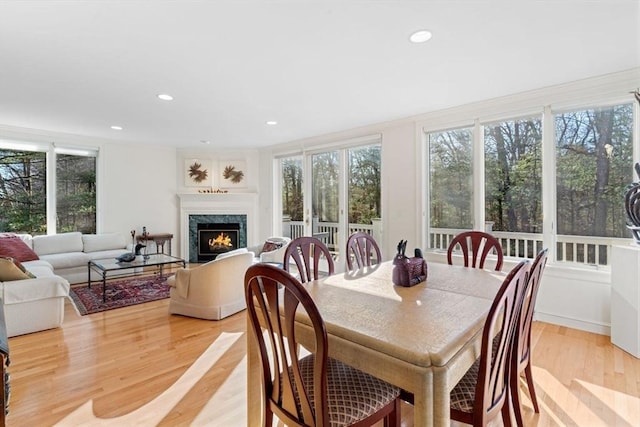 dining space with a high end fireplace and light hardwood / wood-style flooring