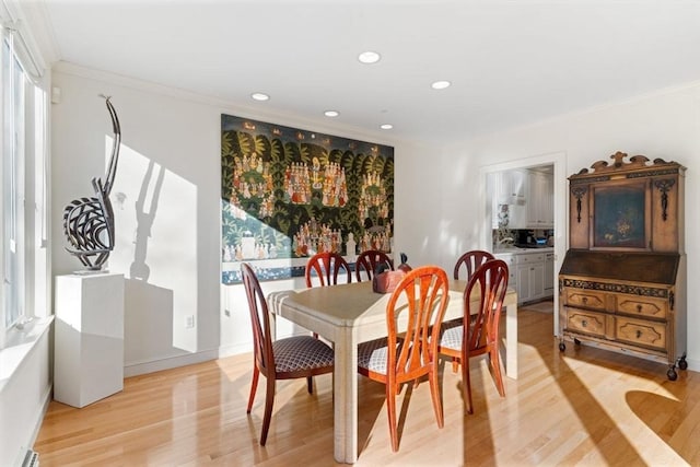 dining space featuring crown molding and light hardwood / wood-style flooring