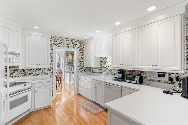 kitchen with sink, white appliances, light hardwood / wood-style flooring, and white cabinets