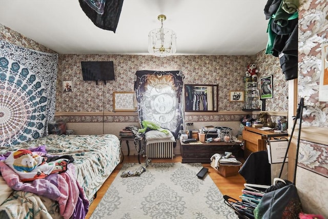 bedroom featuring a notable chandelier, wood finished floors, and wallpapered walls