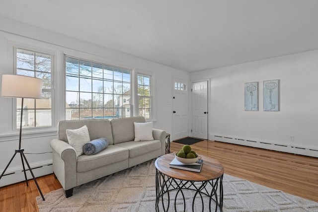 living room featuring a baseboard radiator, a healthy amount of sunlight, and light hardwood / wood-style flooring