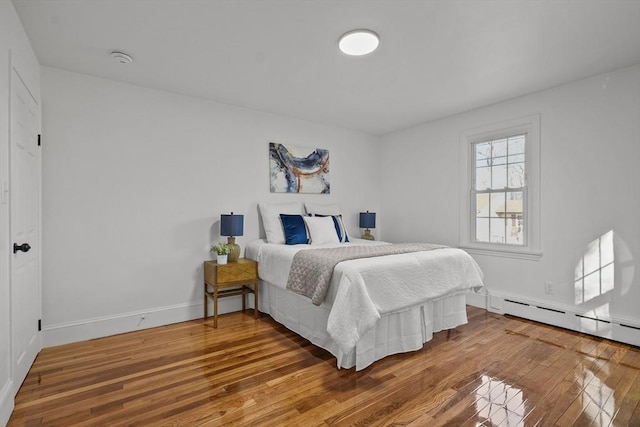 bedroom with a baseboard radiator and hardwood / wood-style floors