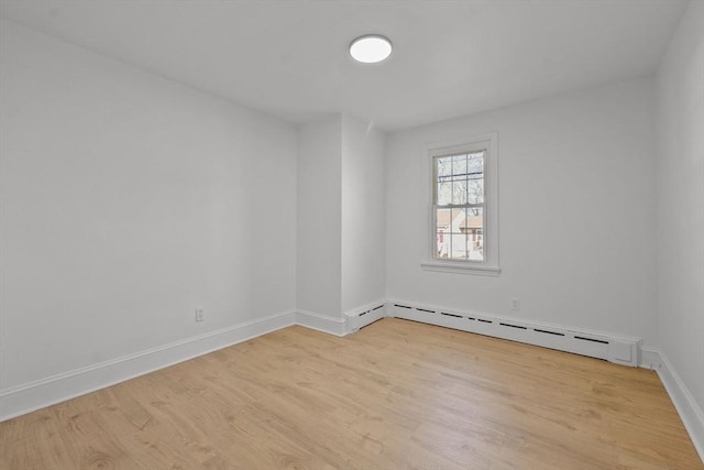 empty room with light wood-type flooring and a baseboard heating unit