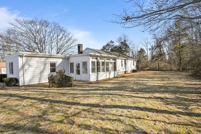 back of house featuring a yard and a sunroom