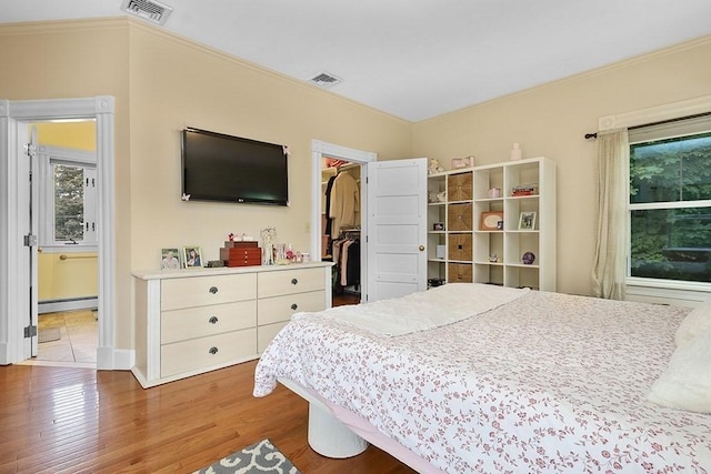 311 Main St, Franklin, MA 02038 - bedroom featuring a baseboard heating unit, wood finished floors, multiple windows, crown molding, and a walk in closet
