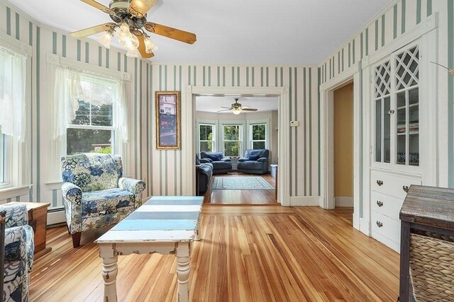 311 Main St, Franklin, MA 02038 - living area with wallpapered walls, light wood finished floors, ceiling fan, baseboard heating, and baseboards