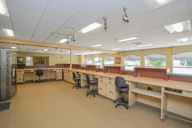 carpeted office space with a paneled ceiling and built in desk