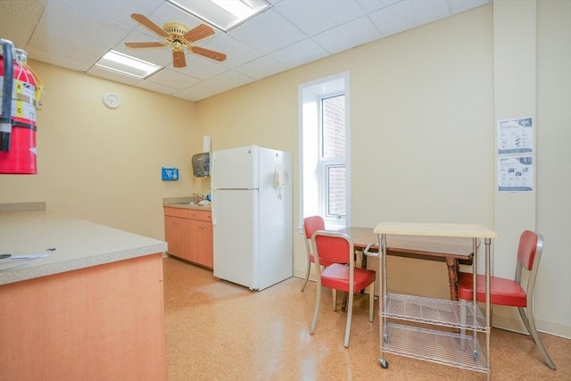 kitchen with ceiling fan, white refrigerator, and a drop ceiling