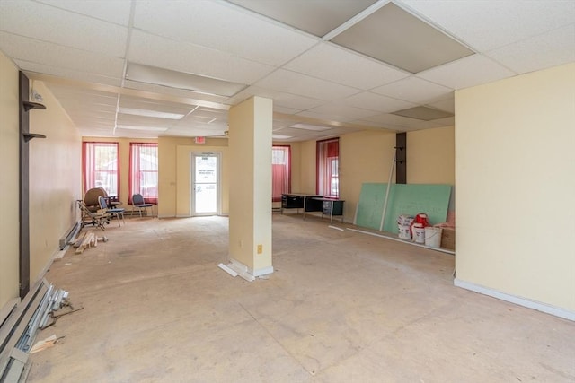 basement featuring baseboard heating and a drop ceiling