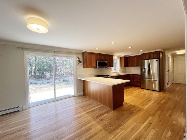 kitchen with stainless steel appliances, a peninsula, a sink, light countertops, and backsplash