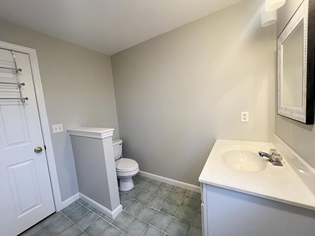 bathroom with toilet, vanity, baseboards, and tile patterned floors