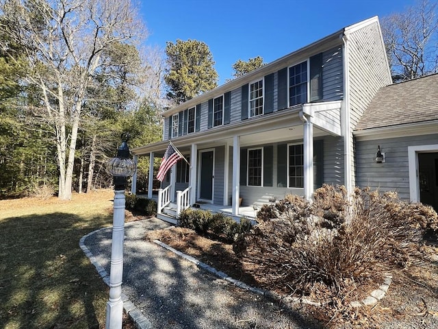 view of front of home featuring a front lawn, a porch, and roof with shingles