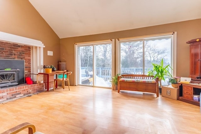 living area featuring a brick fireplace, vaulted ceiling, and wood finished floors