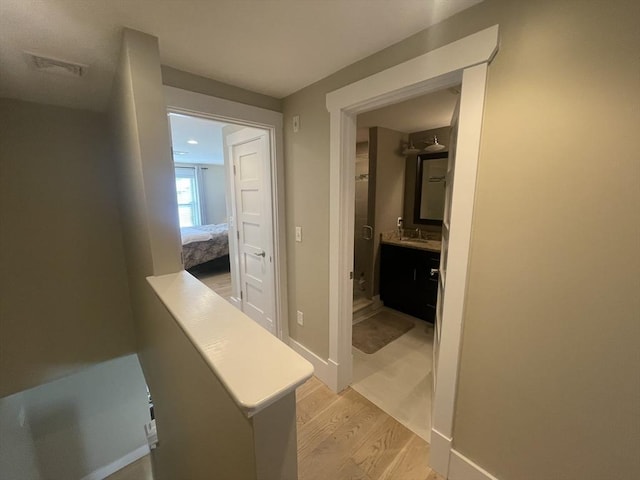 hallway featuring sink and light hardwood / wood-style floors