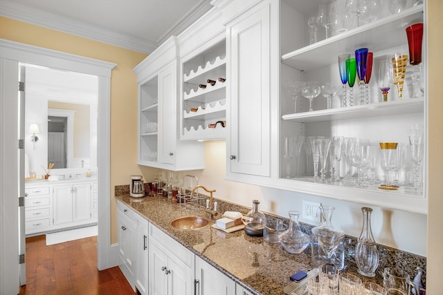 bar featuring dark wood-type flooring, stone countertops, sink, ornamental molding, and white cabinetry