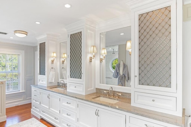bathroom with double vanity, wood finished floors, a decorative wall, and a sink