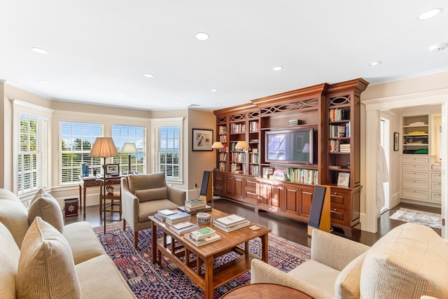 living room featuring wood-type flooring, built in shelves, and ornamental molding