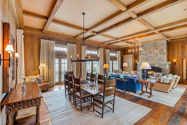 dining space featuring coffered ceiling, beam ceiling, a chandelier, wooden walls, and wood-type flooring