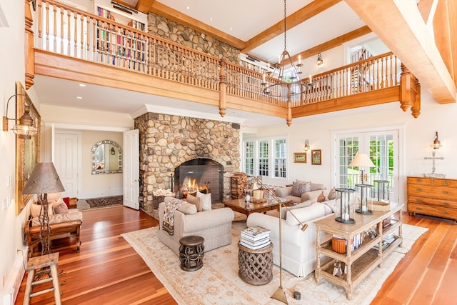 living room featuring a towering ceiling, a stone fireplace, and hardwood / wood-style floors