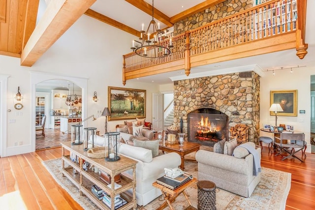 living room with an inviting chandelier, arched walkways, hardwood / wood-style floors, and beamed ceiling