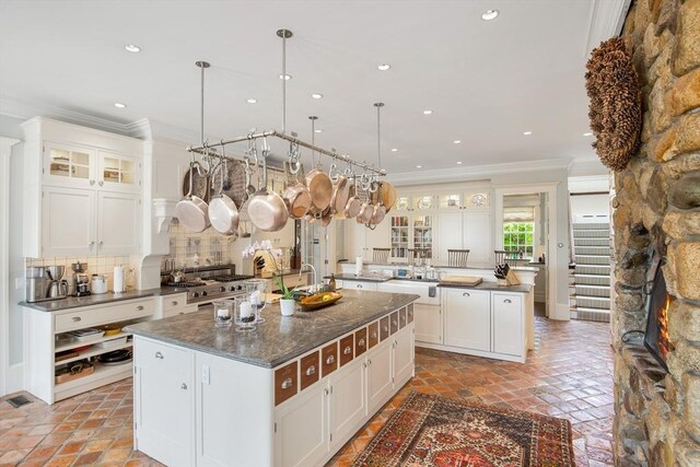 kitchen with white cabinets, a kitchen island with sink, crown molding, and backsplash