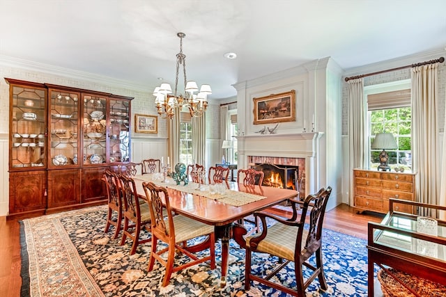 dining space with a notable chandelier, ornamental molding, light hardwood / wood-style floors, and a brick fireplace