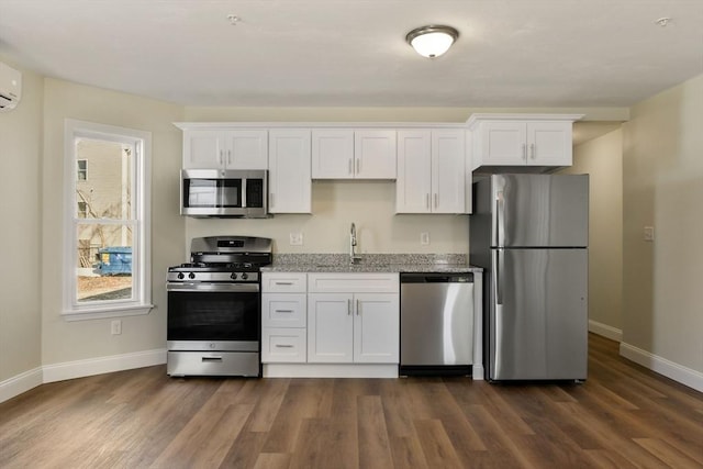 kitchen featuring light stone counters, dark wood-type flooring, appliances with stainless steel finishes, and white cabinets