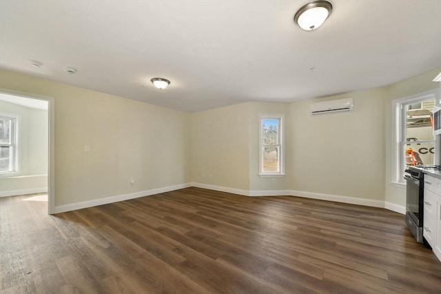 unfurnished room with dark wood-style floors, a wall mounted AC, and baseboards