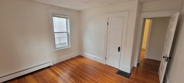 unfurnished room featuring baseboards, a baseboard radiator, and wood finished floors