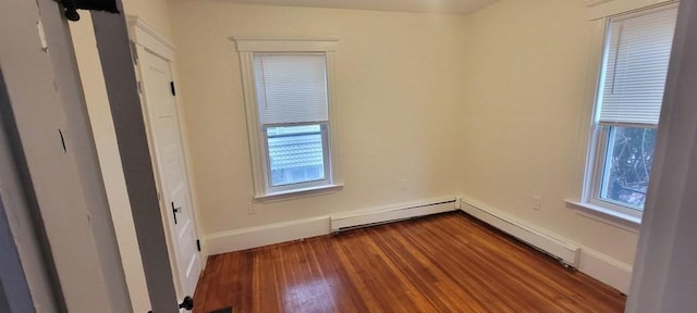 spare room with baseboards, a baseboard radiator, dark wood-style floors, and a healthy amount of sunlight