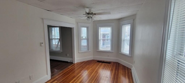 empty room featuring ceiling fan, visible vents, baseboards, a baseboard radiator, and hardwood / wood-style floors