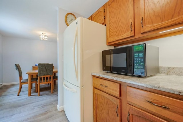 330 Thurston St Unit 330, Wrentham, MA 02093 - kitchen featuring black microwave, freestanding refrigerator, light wood finished floors, light countertops, and brown cabinets