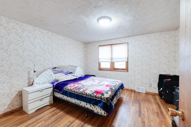 bedroom featuring a textured ceiling and wood-type flooring