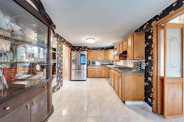 kitchen with a textured ceiling, appliances with stainless steel finishes, decorative backsplash, and sink