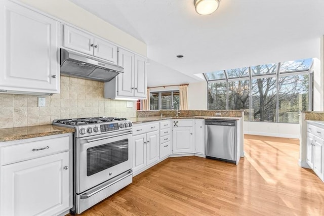 kitchen featuring kitchen peninsula, sink, light hardwood / wood-style flooring, appliances with stainless steel finishes, and white cabinets