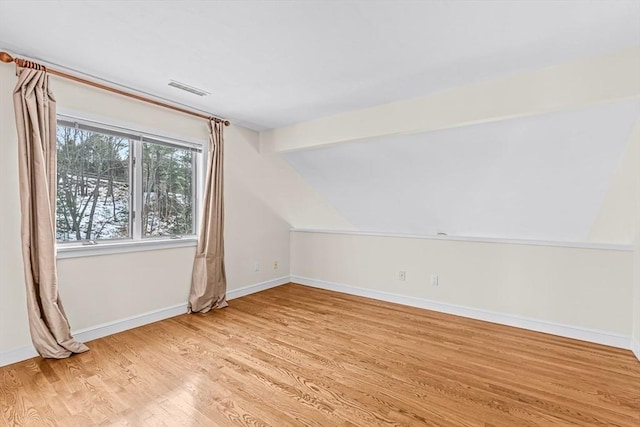 additional living space with vaulted ceiling with beams and light wood-type flooring