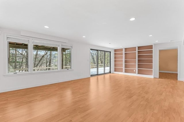 unfurnished living room featuring light wood-type flooring and built in features