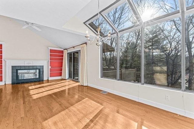 unfurnished sunroom with lofted ceiling, ceiling fan, a fireplace, and a wealth of natural light