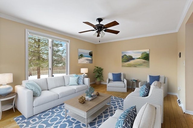 living area with a ceiling fan, crown molding, baseboards, and wood finished floors