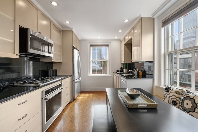 kitchen with cream cabinetry, parquet floors, stainless steel appliances, sink, and decorative backsplash