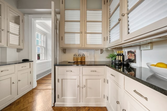 kitchen with dark parquet flooring and white cabinets