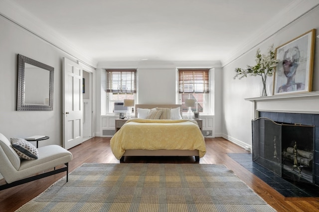 bedroom with wood-type flooring, a fireplace, and crown molding