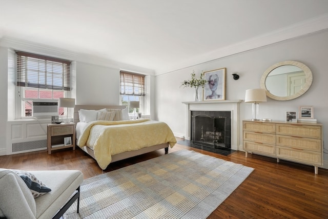 bedroom featuring cooling unit, a tile fireplace, dark hardwood / wood-style flooring, and crown molding