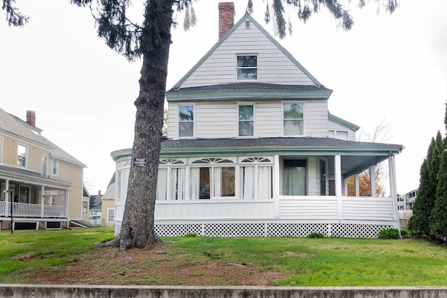 view of front of house featuring a shingled roof, a front lawn, and a chimney