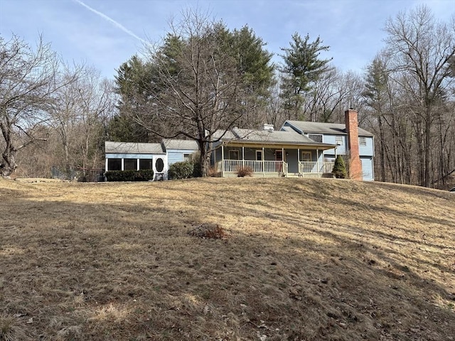 exterior space with covered porch, a chimney, and a yard