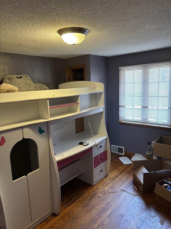 bedroom featuring visible vents, a textured ceiling, and wood-type flooring