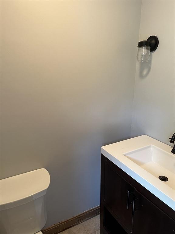 bathroom featuring toilet, vanity, and baseboards