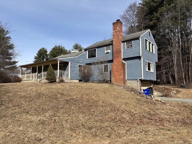 rear view of property featuring a porch and a chimney