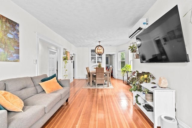 1 King St Unit 3, Boston, MA 02122 - living room featuring a chandelier, light wood finished floors, a wall mounted AC, and a textured ceiling