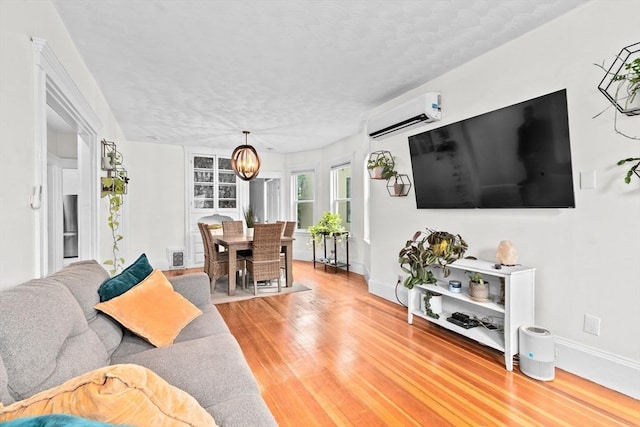 1 King St Unit 3, Boston, MA 02122 - living area with light wood-style floors, a wall unit AC, baseboards, a textured ceiling, and a chandelier